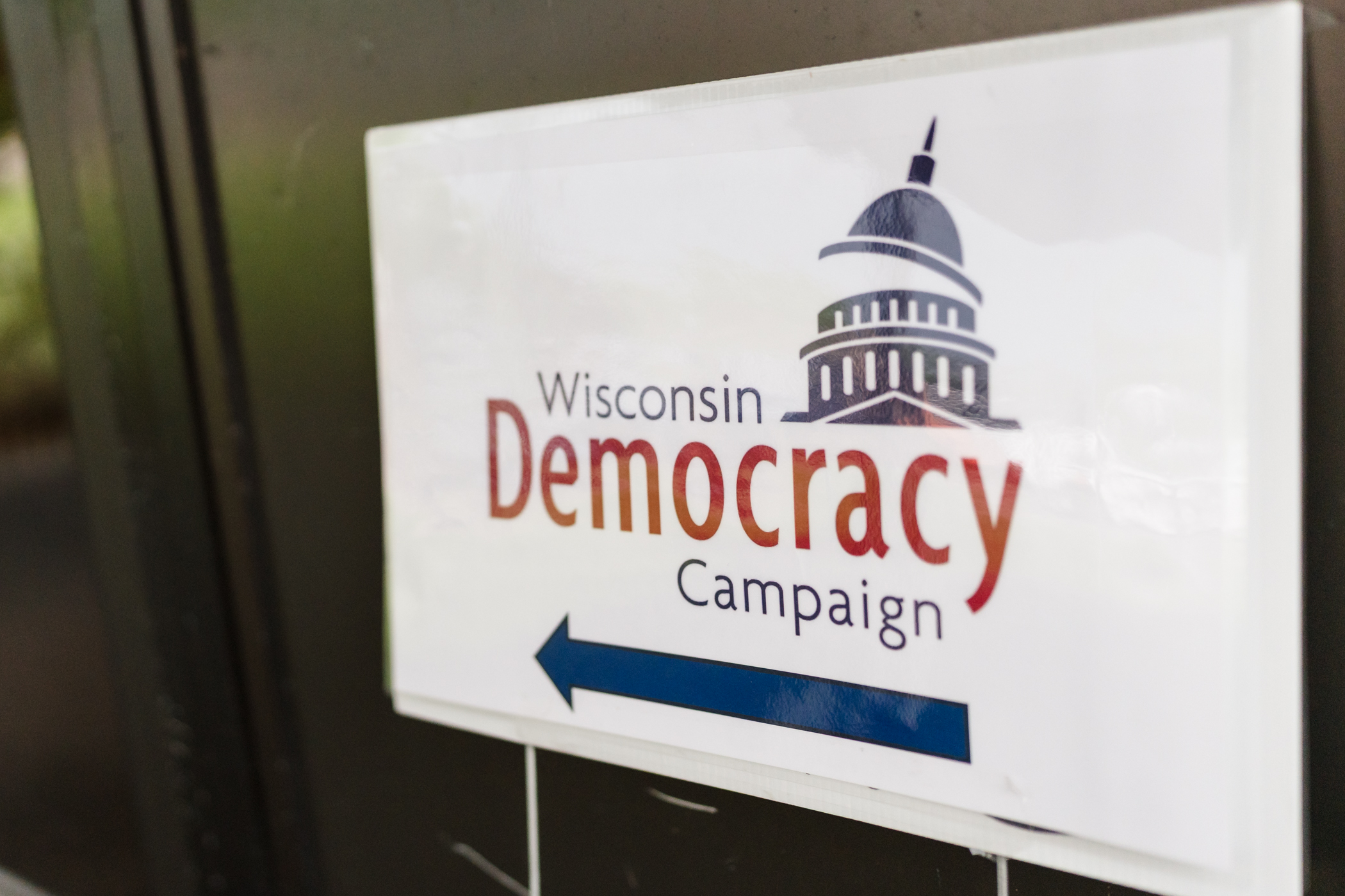a sign with an arrow and text reading Wisconsin Democracy Campaign